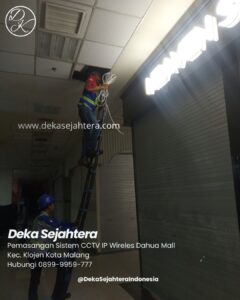 Teknisi melakukan pemasangan CCTV di tenant mall pada malam hari.